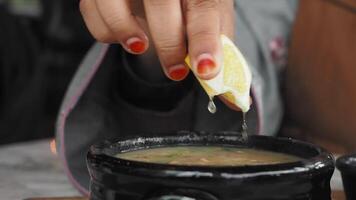 Squeezing a Fresh Lemon into a Bowl of Delicious Soup for Enhanced Flavor and Freshness video