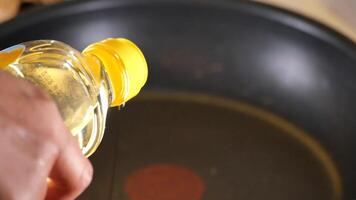 Carefully pouring cooking oil into a pan to prepare for cooking video
