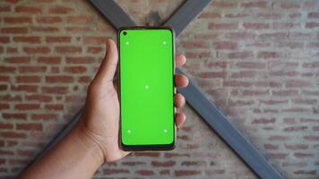 A Hand That is Holding a Smartphone with a Green Screen Intended for Mockups video