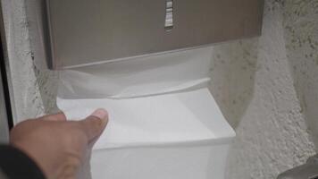 Hand Using Paper Towel Dispenser in a Hygienic Public Restroom with Clean White Tiles video
