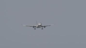 Jet passenger plane with unrecognizable livery in the sky. Airliner descent before landing, front view, long shot video