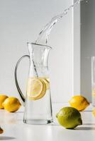 A pitcher of lemonade with a splash of water on top and lemons in the background. photo