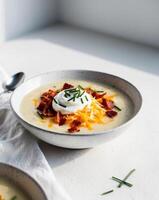Loaded Baked Potato Soup with Sour Cream Cheddar Cheese Bacon Bits and Chives. photo