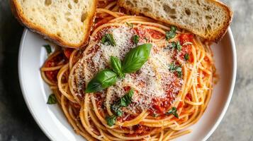 Serving of spaghetti topped with marinara sauce and grated cheese, served with garlic bread, food setting photo
