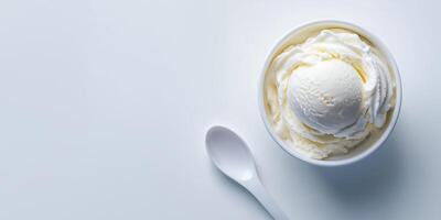 Small bowl of vanilla ice cream next to a simple white spoon, food setting photo
