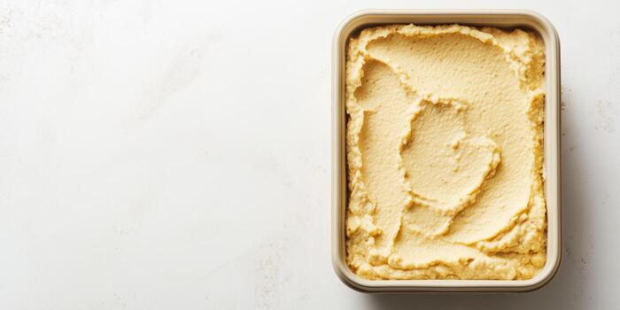 Hummus displayed in a rectangular container with an even texture and no extra components, meal photography photo