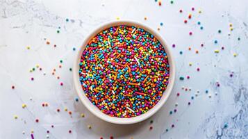 An overhead view of a bowl containing rainbow jimmies, centered on a white surface, culinary photography photo