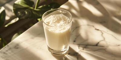 Glass of probiotic yogurt drink with an even consistency, placed on a marble table, meal photography photo