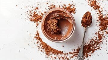 Jar of cocoa spread on white background with metal spoon beside it, food setting photo