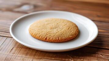 Plain round cookie on a white plate on a wooden table, food setting photo