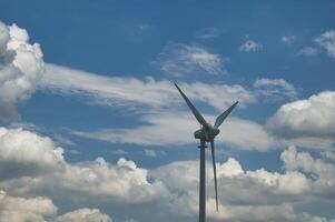 Wind turbine against a backdrop of cloudy and clear blue sky capturing renewable energy photo
