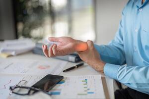 Office worker experiences wrist pain while analyzing data reports in a workspace environment photo