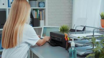 Busy home office setup with a woman printing documents and organizing her workspace in a modern environment video