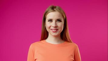Young Woman Smiling and Blinking Against a Bright Pink Background video