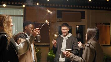 Friends celebrate New Year's Eve with sparklers at a lively outdoor gathering in the city during the countdown to midnight video