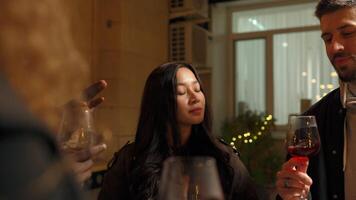 A lively gathering with friends relishing wine and conversation at a cozy outdoor setting in the evening ambiance video