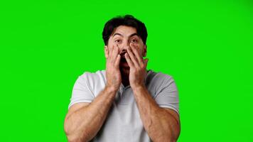 Man shows shock and disbelief with hands on face against bright green background video