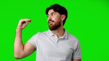 Man with beard gestures while standing against a green background during a casual setting video