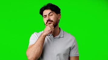 jovem homem contemplando com pensativo expressão contra uma brilhante verde fundo durante uma criativo projeto video