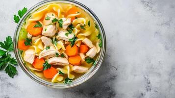 Chicken noodle soup in a glass bowl with chicken, noodles, and vegetables, culinary photography photo