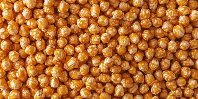 Caramel corn arranged on a plain surface, with individual coated kernels easily visible, food setting photo
