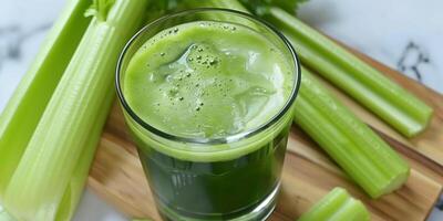 Clear glass of cold-pressed celery juice placed on a cutting board, with celery stalks surrounding it, food photography photo