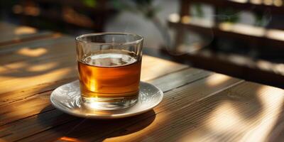 Clear glass of unsweetened herbal tea, placed on a white saucer on a wooden surface, food photography photo