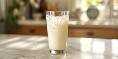 Clear glass of kefir with visible bubbles, sitting on a marble countertop, gastronomy photography photo