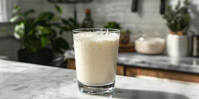 Clear glass of kefir with visible bubbles, sitting on a marble countertop, meal photography photo