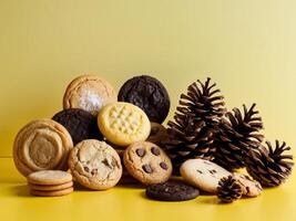 A yellow background with a variety of cookies and pine cones. photo