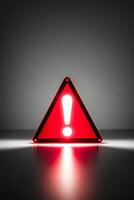 glowing neon red triangle sign with exclamation point on dark warning indicator alert signal. photo