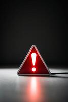 glowing neon red triangle sign with exclamation point on dark warning indicator alert signal. photo