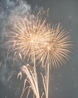 Dynamic golden fireworks with glowing particles and explosive sparks on a black background. photo