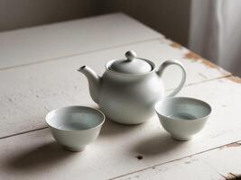 A teapot and two cups sitting on a wooden table. photo