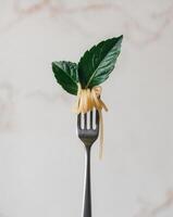 A fork full of spaghetti with a green leaf on top. photo