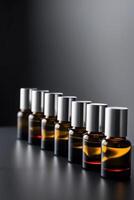 Bottles of aromatherapy essential oil in a row on dark background. photo