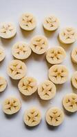 Multiple banana slices arranged in a star like pattern on a white background Vertical Mobile Wallpaper photo
