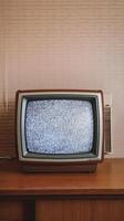 Retro CRT television on wooden surface displays static, evoking nostalgic simplicity Vertical Mobile Wallpaper photo