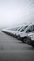 White vans parked in line, first van slightly blurred emphasizing depth and scale Vertical Mobile Wallpaper photo