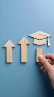 Sequence of three wooden cutouts, graduation cap held by human hand highlights importance Vertical Mobile Wallpaper photo