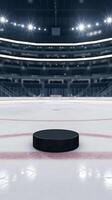Hockey puck on ice, arena illuminated under bright lights, empty seats visible Vertical Mobile Wallpaper photo