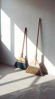 Empty room with sunlight casting shadows, brooms leaning in serene simplicity Vertical Mobile Wallpaper photo