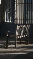Weathered bench facing dimly lit bars, casting contemplative, serene shadows Vertical Mobile Wallpaper photo