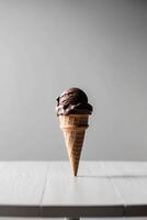 Chocolate ice cream cone is sitting on a table. photo