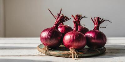 Four whole red onions with roots resting on wooden table. photo