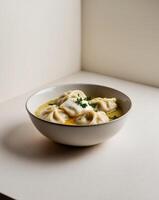 Dumplings with butter and sour cream garnished with parsley and black pepper served in a ceramic bowl. photo