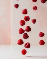 Various falling fresh ripe raspberries on light pink background horizontal composition. photo