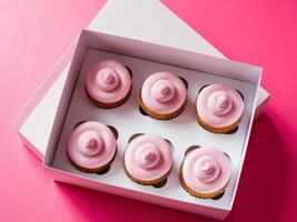 Box of pink frosted cupcakes on a bright pink background. photo