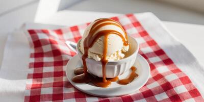 Butter pecan ice cream with caramel drizzle on classic red checkered tablecloth. photo