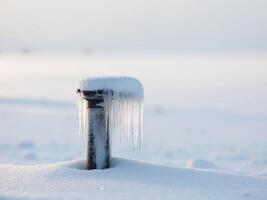 Icy pipe covered in snow and icicles in winter landscape. photo